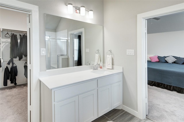 ensuite bathroom featuring a walk in closet, a stall shower, ensuite bath, lofted ceiling, and vanity