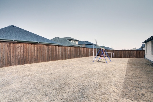 view of yard with a fenced backyard and a playground