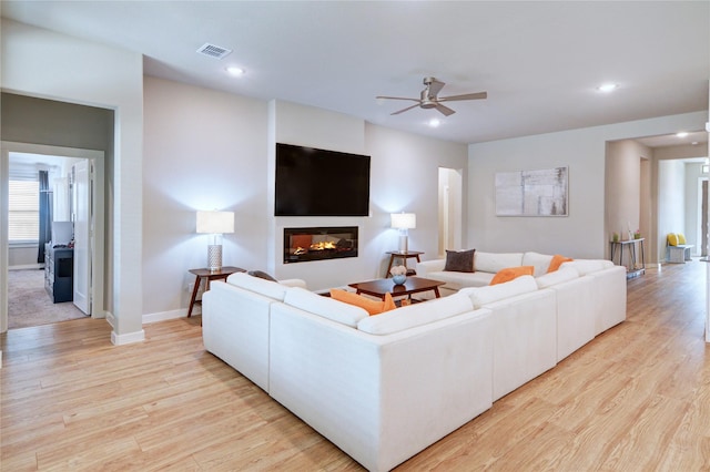 living room with visible vents, ceiling fan, recessed lighting, light wood-style flooring, and a glass covered fireplace