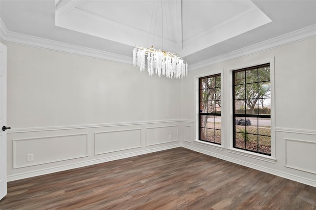 unfurnished dining area featuring dark wood finished floors, a decorative wall, a raised ceiling, a notable chandelier, and crown molding