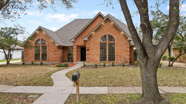 ranch-style house featuring brick siding, a shingled roof, and a front yard