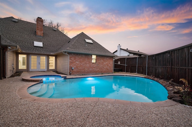view of pool with french doors, a fenced backyard, and a pool with connected hot tub