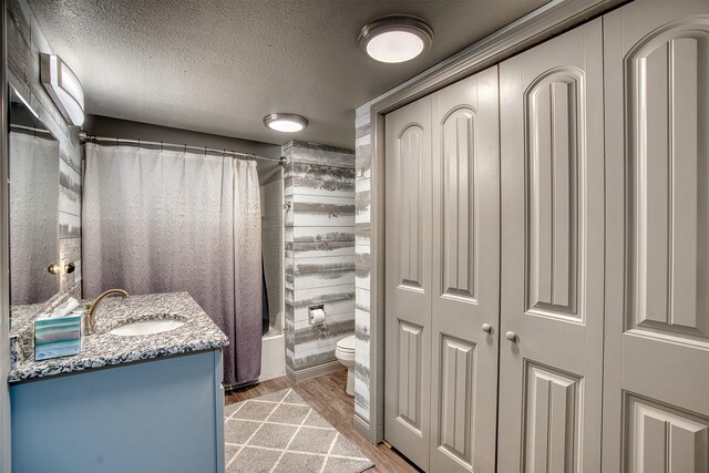 237 Runaway Bay Dr, Runaway Bay, TX 76426 - bathroom with wood finished floors, shower / bath combo with shower curtain, toilet, vanity, and a textured ceiling