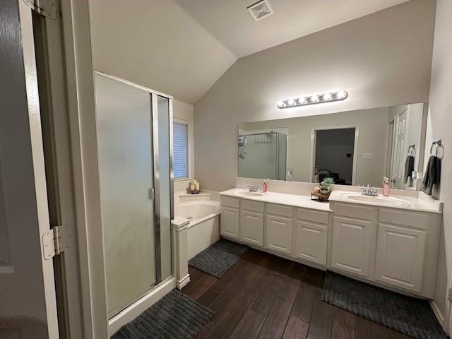 1615 Summerfield Dr, Allen, TX 75002 - bathroom with wood finished floors, a shower stall, vaulted ceiling, double vanity, and a garden tub