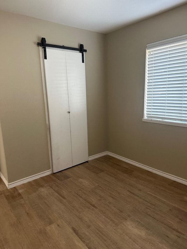 2612 Lemmontree Ln, Plano, TX 75074 - unfurnished bedroom featuring wood finished floors, a barn door, baseboards, and a closet