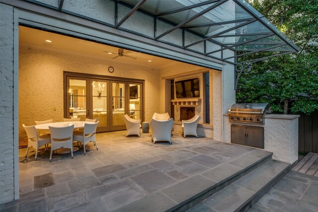 view of patio with exterior kitchen, french doors, outdoor dining area, an outdoor fireplace, and a grill