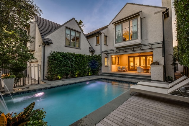 rear view of house with a fenced in pool, a wooden deck, and stucco siding