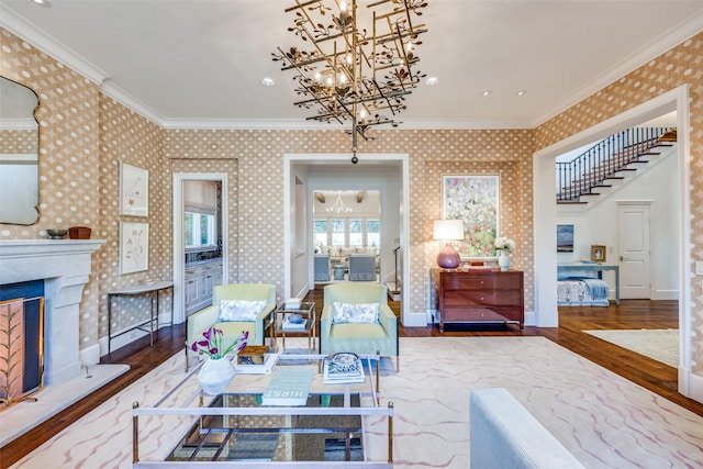 living room with wood finished floors, a chandelier, ornamental molding, and wallpapered walls