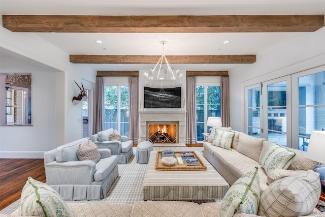 living room with beam ceiling, a large fireplace, baseboards, and wood finished floors