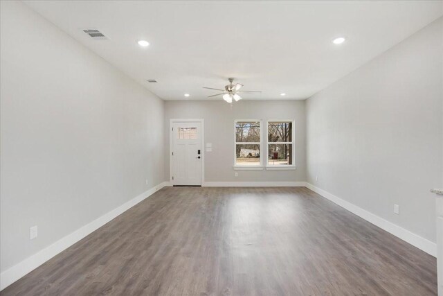 spare room with wood finished floors, baseboards, visible vents, and ceiling fan