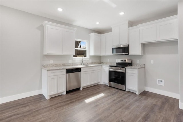kitchen featuring white cabinets, baseboards, appliances with stainless steel finishes, and a sink