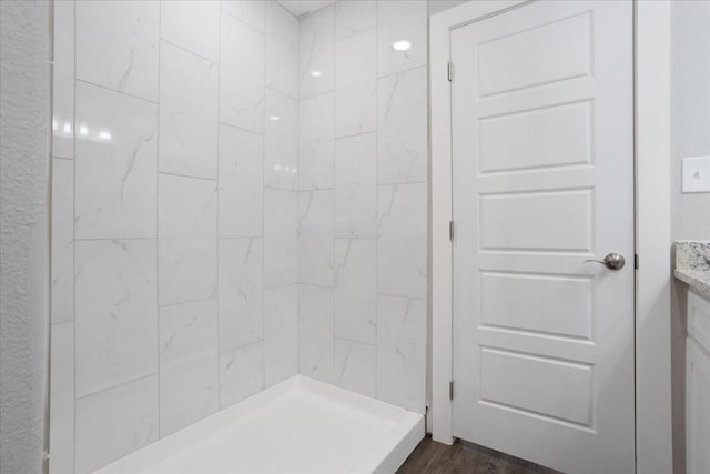 bathroom with vanity, wood finished floors, and a tile shower