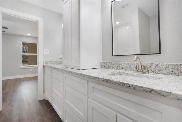 full bathroom featuring visible vents, baseboards, double vanity, wood finished floors, and a sink