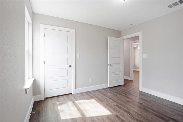 unfurnished bedroom with visible vents, baseboards, and wood finished floors