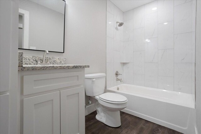 bathroom featuring toilet, wood finished floors, vanity, and shower / tub combination