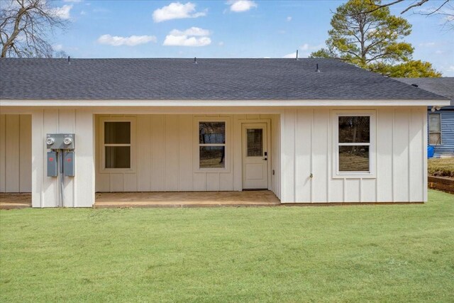 rear view of house featuring a lawn, board and batten siding, and a shingled roof