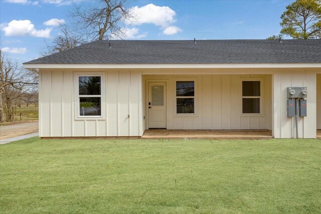 view of front of property featuring roof with shingles, board and batten siding, and a front lawn