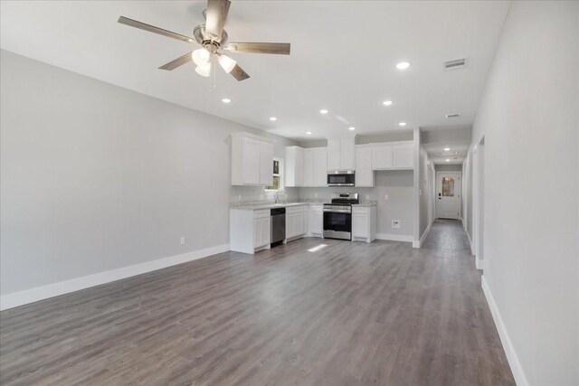 unfurnished living room featuring visible vents, baseboards, and wood finished floors