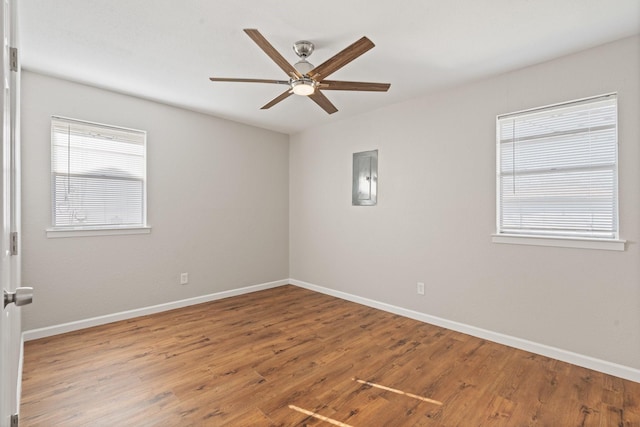 spare room featuring electric panel, wood finished floors, baseboards, and ceiling fan