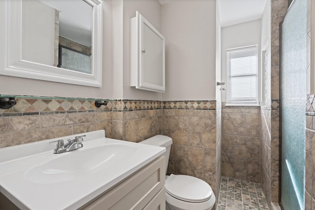 full bathroom featuring wainscoting, a stall shower, toilet, and vanity