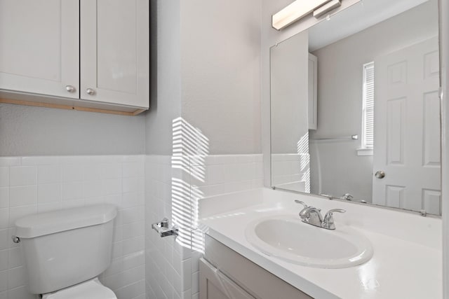 bathroom featuring vanity, tile walls, and toilet