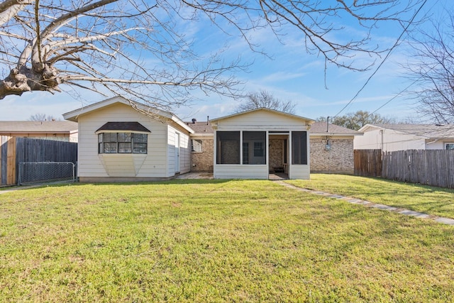 rear view of house with a yard, a fenced backyard, and a sunroom