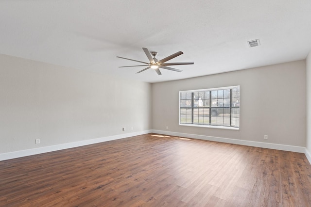 empty room featuring visible vents, baseboards, dark wood-style floors, and a ceiling fan