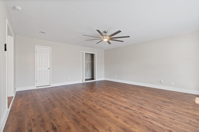 empty room featuring dark wood-style floors, baseboards, visible vents, and ceiling fan