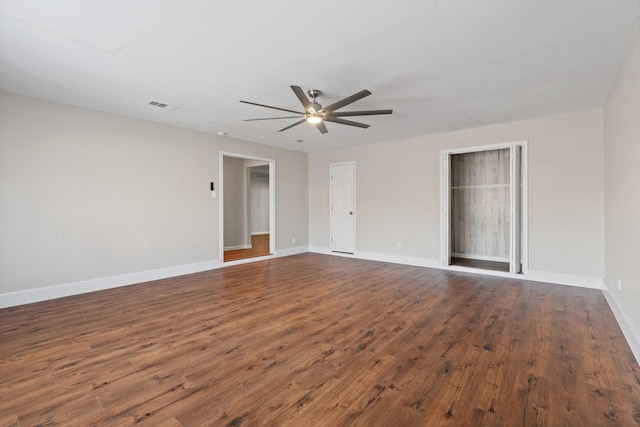 unfurnished room with visible vents, baseboards, dark wood-style floors, and a ceiling fan