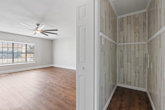 empty room featuring baseboards, wood finished floors, and a ceiling fan