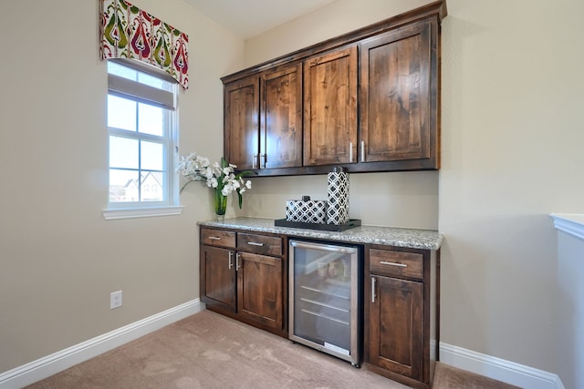 bar with baseboards, light carpet, plenty of natural light, and beverage cooler