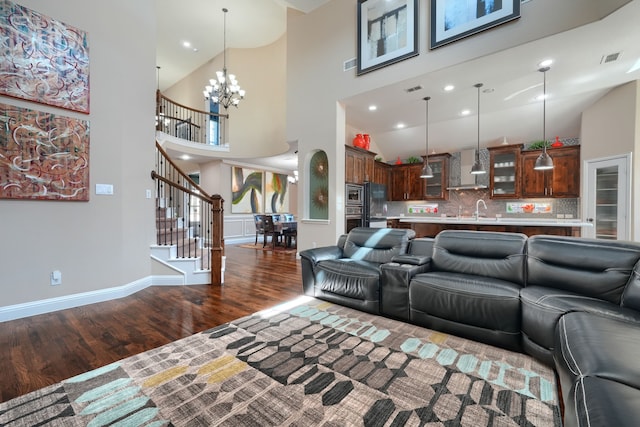 living area featuring visible vents, baseboards, wood finished floors, stairway, and an inviting chandelier