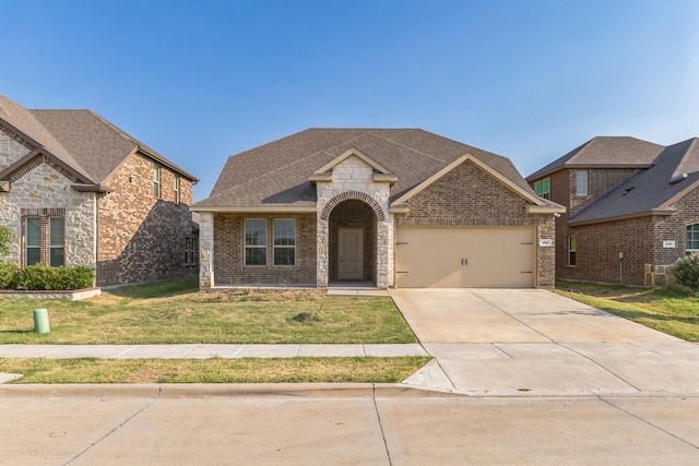 view of front of home with driveway, a front yard, a shingled roof, a garage, and brick siding