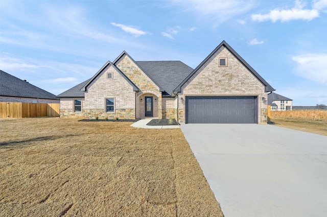901 Shirley Jean Ln, Collinsville, TX 76233 - french country style house featuring a front lawn, driveway, stone siding, fence, and an attached garage