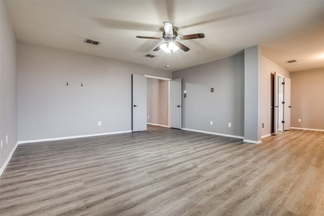spare room featuring baseboards, visible vents, a ceiling fan, and wood finished floors