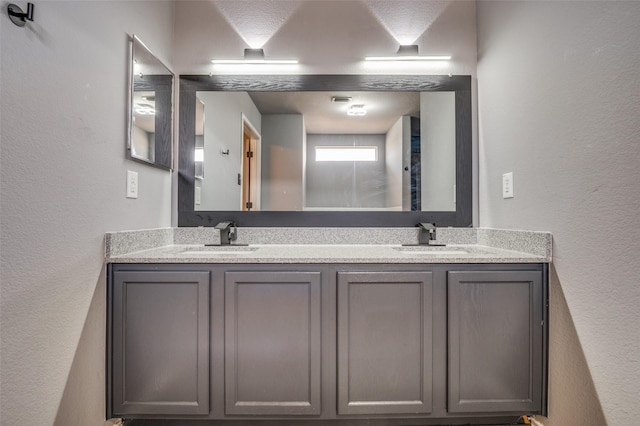 bathroom with a textured wall, double vanity, and a sink