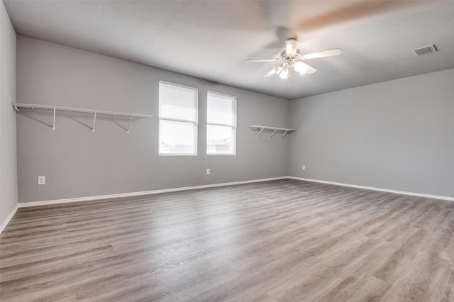 empty room with baseboards, ceiling fan, visible vents, and wood finished floors
