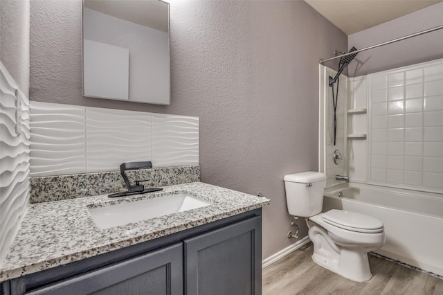 bathroom with toilet, wood finished floors, vanity, a textured wall, and shower / tub combination