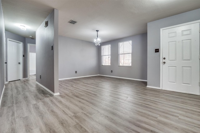 interior space with baseboards, visible vents, wood finished floors, and an inviting chandelier