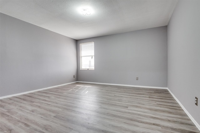 spare room with baseboards, wood finished floors, and a textured ceiling