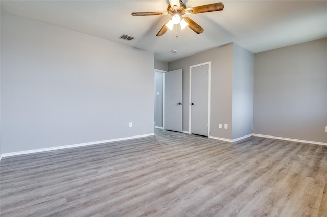 unfurnished bedroom featuring baseboards, visible vents, a ceiling fan, and wood finished floors
