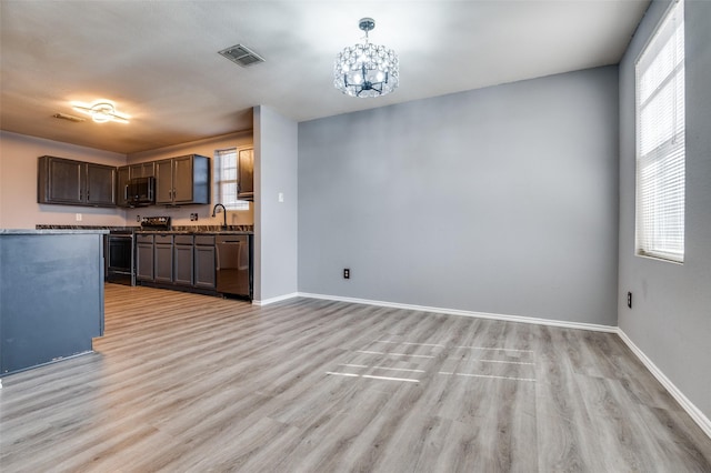 kitchen with visible vents, light wood finished floors, stainless steel appliances, a sink, and an inviting chandelier