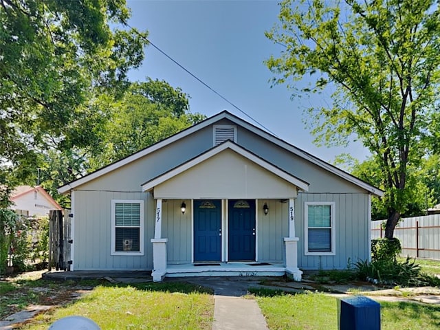 bungalow featuring board and batten siding, covered porch, and fence