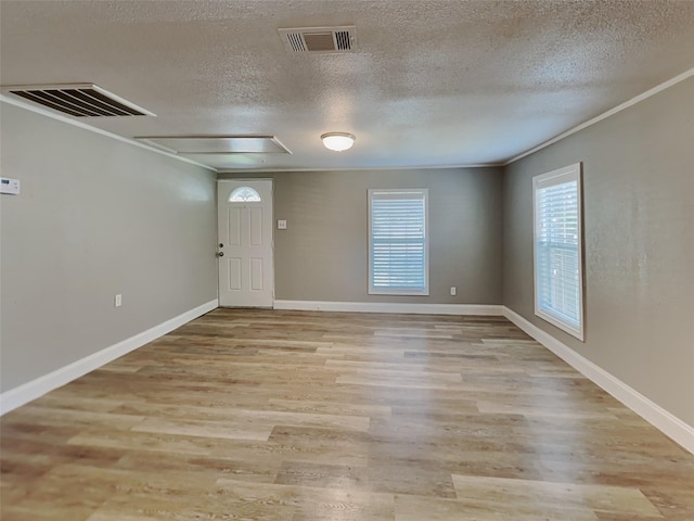 unfurnished room with visible vents, attic access, and light wood-style floors
