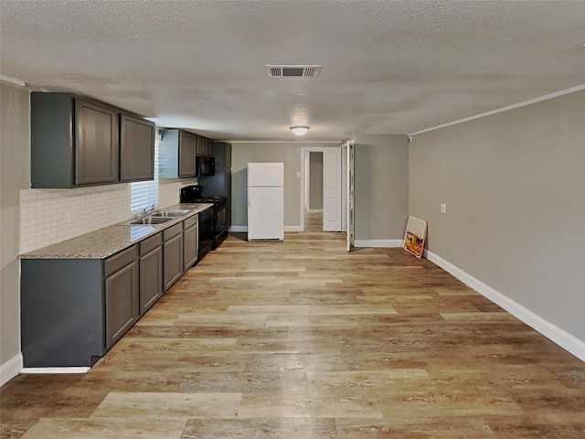 kitchen featuring visible vents, backsplash, light wood-style flooring, black appliances, and a sink