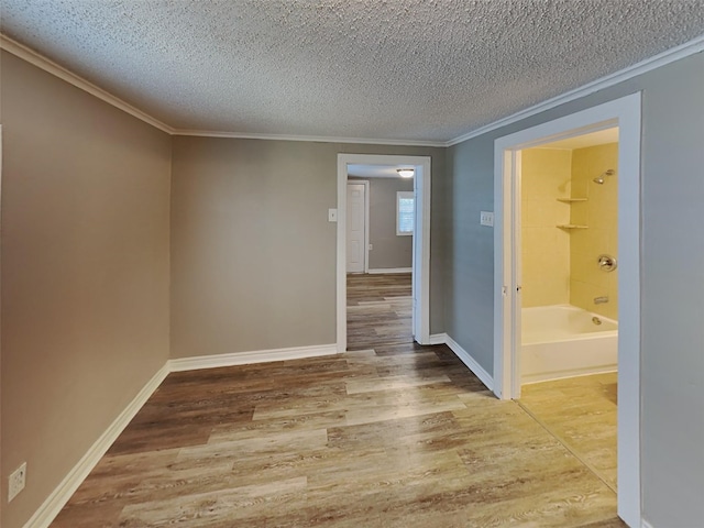 unfurnished room featuring baseboards, a textured ceiling, wood finished floors, and crown molding