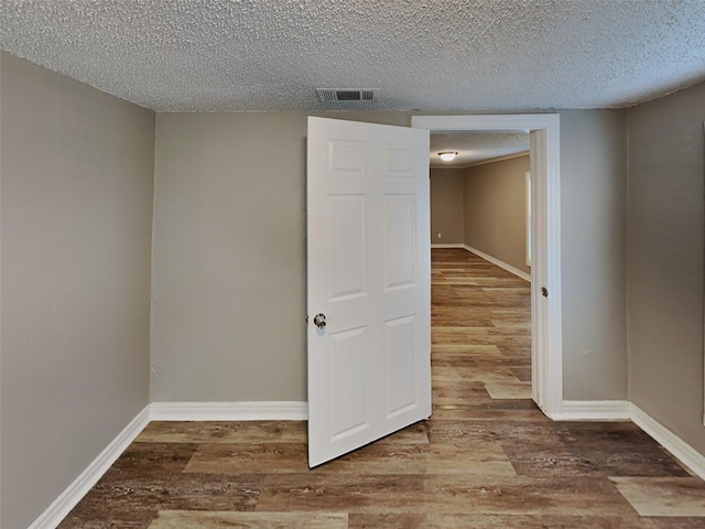 unfurnished room featuring wood finished floors, visible vents, and baseboards