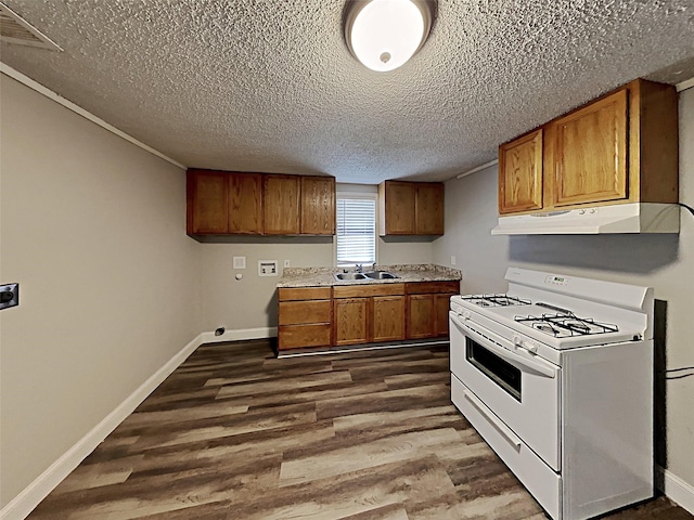 kitchen featuring under cabinet range hood, dark wood finished floors, white range with gas stovetop, brown cabinets, and a sink