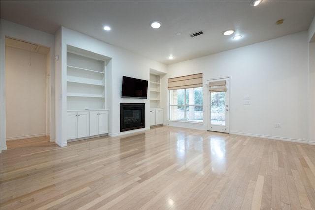 1505 Valley Creek Rd, Denton, TX 76205 - unfurnished living room featuring built in features, baseboards, recessed lighting, a glass covered fireplace, and light wood finished floors