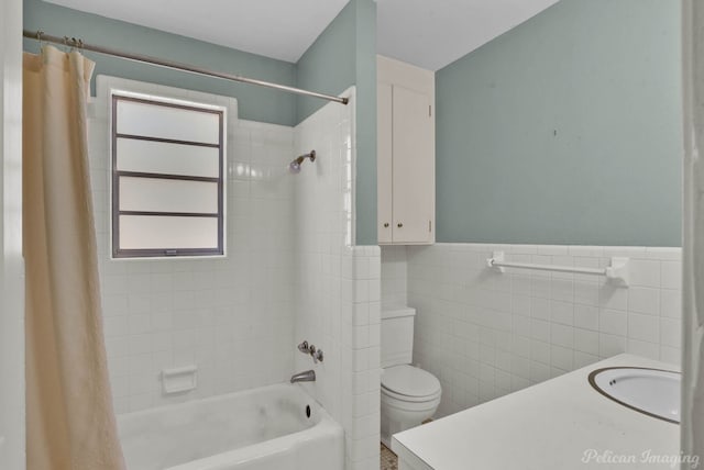 bathroom featuring shower / tub combo with curtain, toilet, tile walls, wainscoting, and vanity